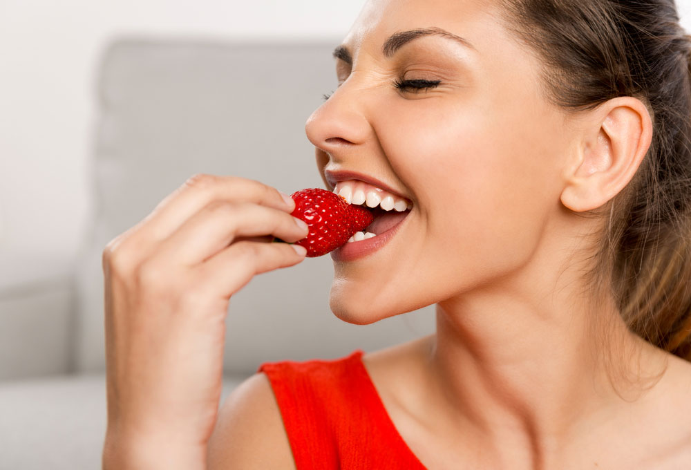 a woman eating strawberry
