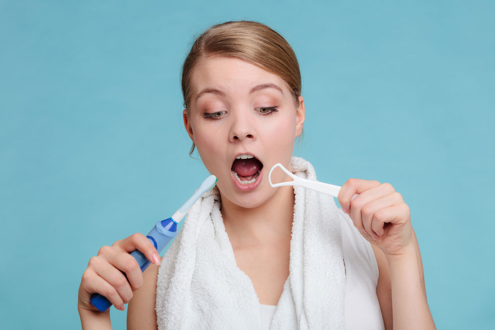 Female using a toothbrush to clean her teeth in a bathroom