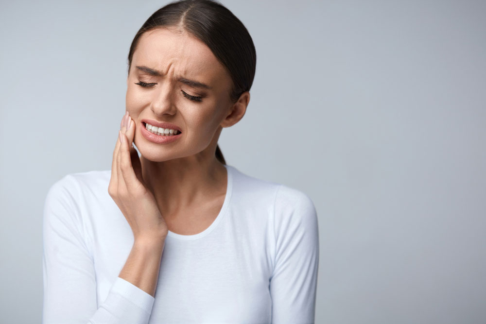 a woman holding her teeth in pain