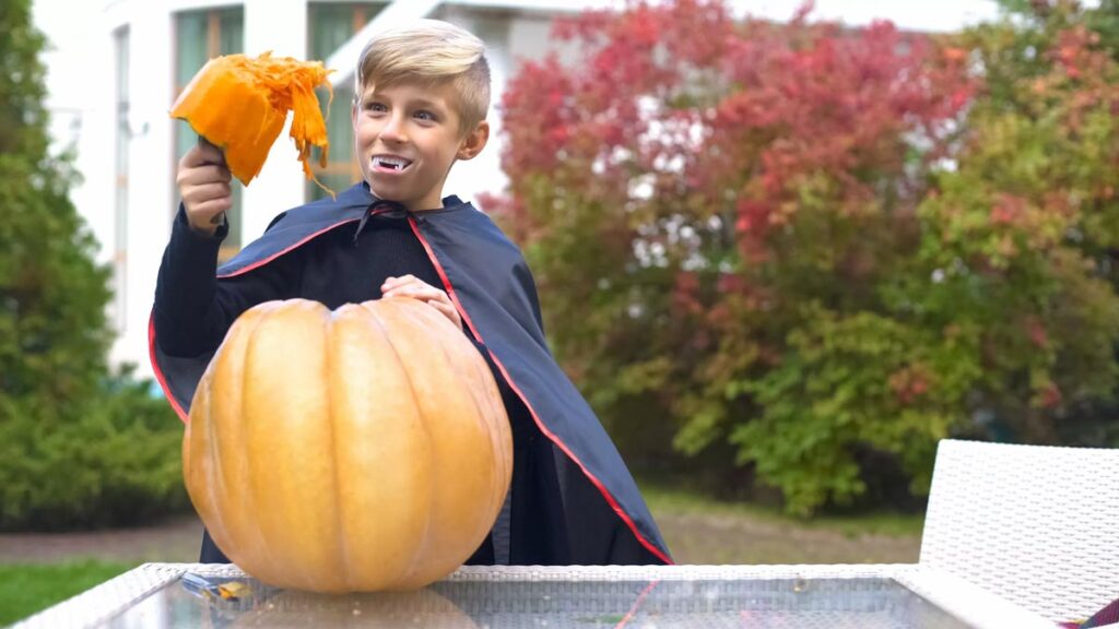 boy dressed as vampire eating pumpkin