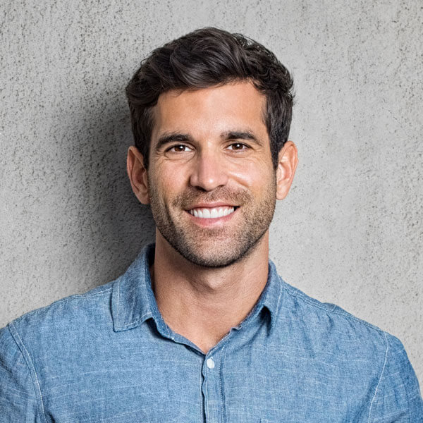 Attractive man with nice smile standing against concrete wall